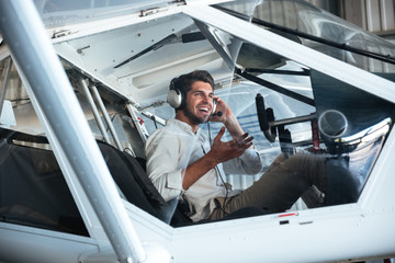 Man pilot sitting in small plane and talking using headset © Drobot Dean