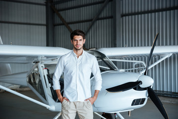 Confident man standing in front of small aircraft