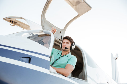 Confident young man pilot in small plane