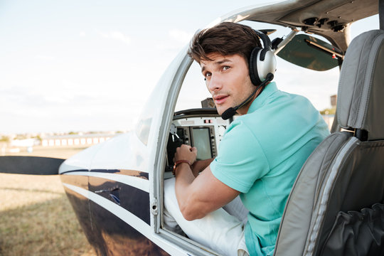 Man pilot sitting in cabin of small airplane