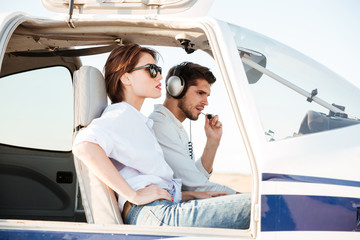 Young pilot and beautiful stewardess sitting inside airplane cabin