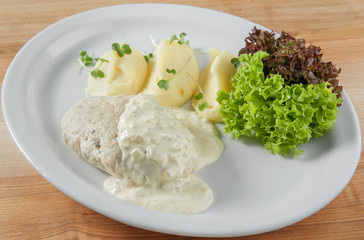 dish meal with mashed potatoes, fish cutlet poured sauce and sal