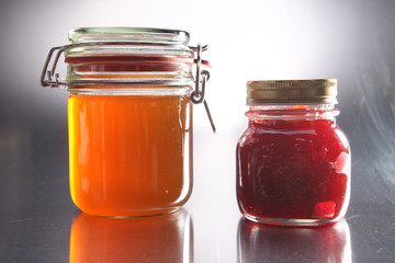 Jars of jam and honey on a wooden table.