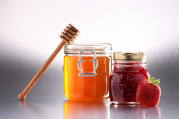 Jars of jam and honey on a wooden table.