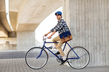 Naklejka premium young hipster man with bag riding fixed gear bike
