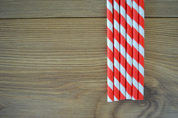 Red and White striped party straws on a wood background texture