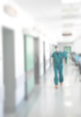 Doctors and nurses walking in hospital hallway, blurred motion.