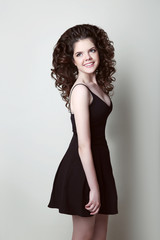 happy teen girl with curly hair isolated on studio grey backgrou