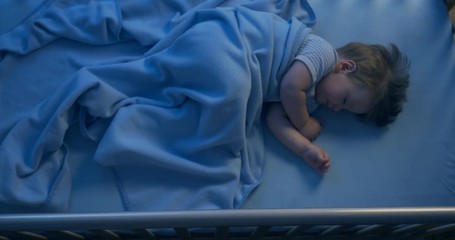 Vertical shot of an adorable baby sleeping in the night time - lights are turned off.
 - Powered by Adobe