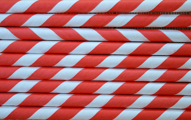 Red and White striped party straws on a wood background texture