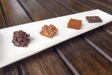 Various chocolates in white dish on wood table.