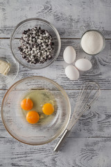 Eggs and whisk on wooden table