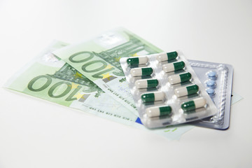 drug pills, medicaments, on one hundred dollars -euros  banknotes as a background. Money and health still life concept.