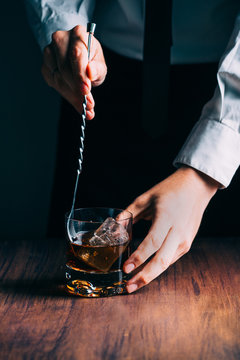 Man Preparing a Glass of whiskey on a wooden table