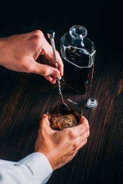Man Preparing a Glass of whiskey on a wooden table