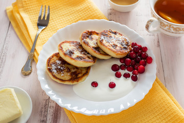 Curd fritters with cranberries on a white plate