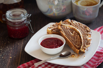 Slices of a swiss roll and jam on a white plate