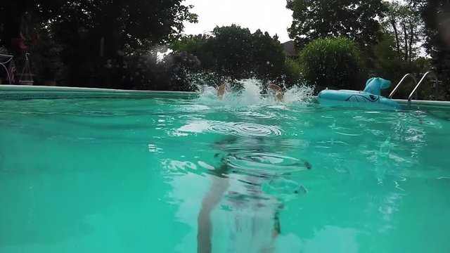 Young man dives into swimming pool, slow motion summer fun.