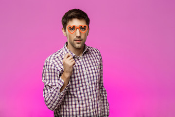 Fototapeta premium Young man wearing fake glasses over purple background. Birthday party.
