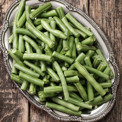 Bunch of freshly picked green beans on a wooden surface.