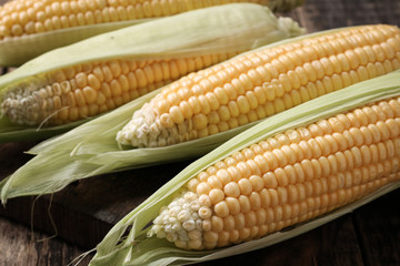 Fresh corn on cobs on rustic wooden table, closeup