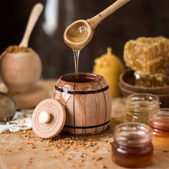 Obraz na płótnie Canvas Honey background. Natural honey comb, glass jarand wooden bowls. On wooden rustic table. Soft focus