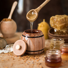 Obraz na płótnie Canvas Honey background. Natural honey comb, glass jarand wooden bowls. On wooden rustic table. Soft focus