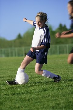 Teenage girl playing soccer on field