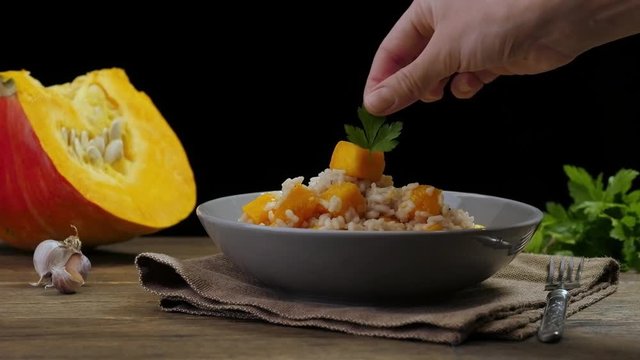Women's hands decorating the dish. Pumpkin risotto