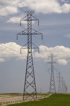 Metal Power Lines In A Row With A Blue Sky And Clouds; Calgary, Alberta, Canada