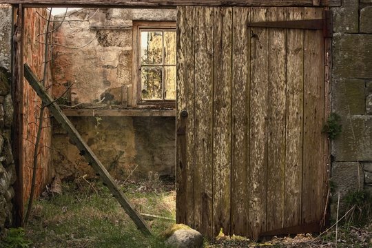 Northumberland, England; An Abandoned Building In Ruins With A Broken Wooden Door