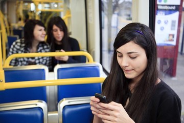 Portland, Oregon, United States Of America; Three Teenage Girls Using Their Cell Phone And Listening To Music While Sitting On Public Transportation