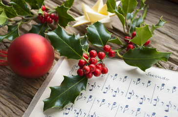 Fototapeta premium Sehr altes, handgeschriebenes Notenblatt mit roter Weihnachtskugel, Ilex Zweig und Weihnachtsstern, Weihnachten, xmas 