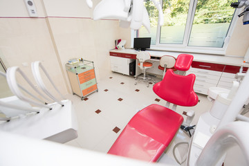 Dental red chair with equipment and other accessories used by dentists in the dental cabinet. Close-up