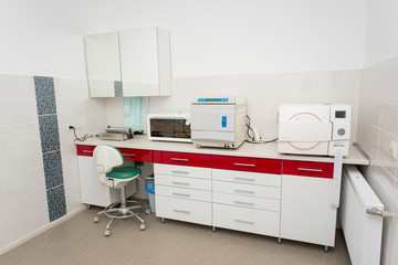 Modern sterilization room for the handling of dental instruments. Table with a packaging machine, ultraviolet shelf, sterilizer, autoclaving