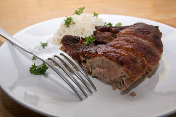 fried duck breast and rice with parsley garnish and a fork on a white plate