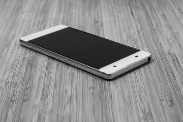 Smartphone weiß auf Holztisch, Bambus, schwarz weiß