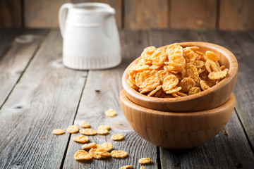 Cornflakes for breakfast in a bamboo plate on old wooden background. Selective focus.