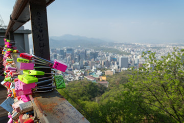 Close-up of colorful love locks at an observation point at the Namsan Hill (or Namsan Park or Namsan Mountain) and view of the city in Seoul, South Korea.