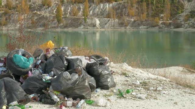 The dump in nature / Black plastic bags with garbage, old tires, plastic and glass bottles 
