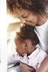 Fototapeta premium Mother holding baby at the window and smiling