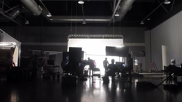 Wide angle capturing unrecognizable film and photo crew working on professional studio shoot.