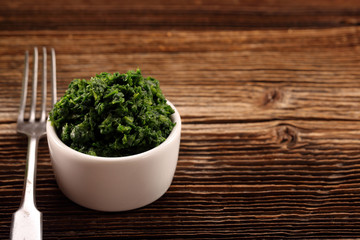Fresh chopped spinach in a bowl on wooden background