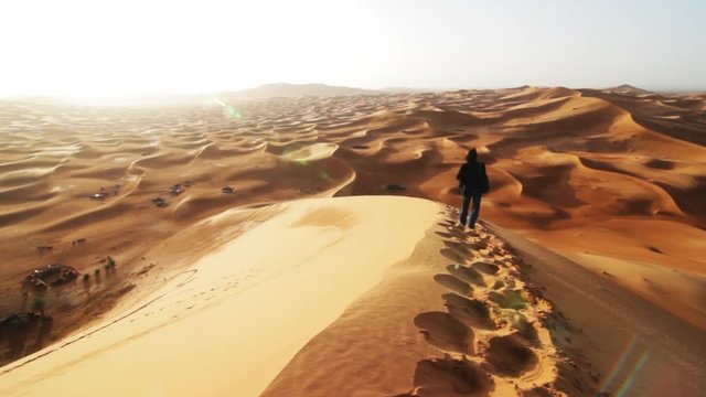 Woman walks a sand dune in Sahara, Morocco.