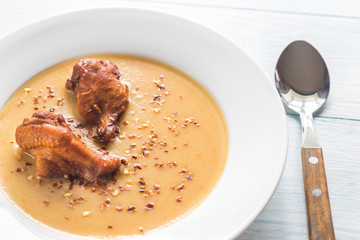 Portion of pea cream soup with smoked chicken wings