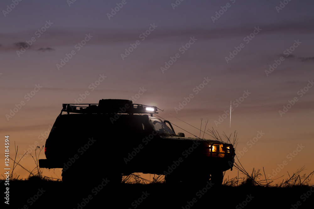 Wall mural SUV silhouette on sunset sky background