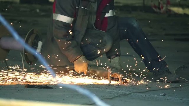 Construction worker cuts metal with a angle grinder on a construction site, slow motion