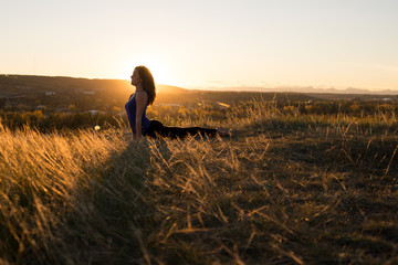 Woman doing yoga upward dog pose during sunset