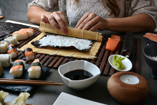 Woman preparing sushi rolls at home