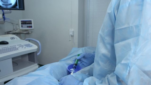Interventional radiologist injecting embolization material, embolization treatment